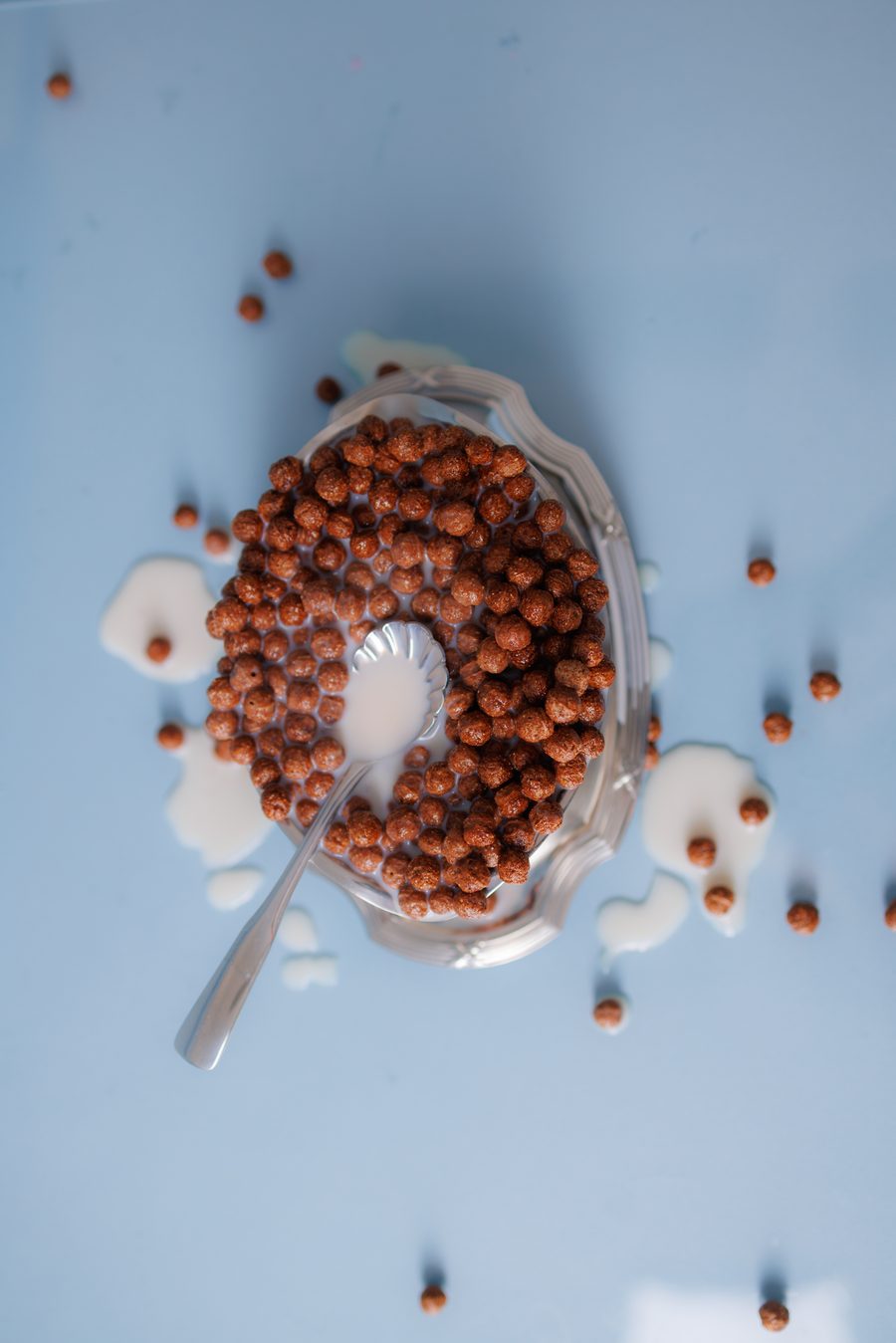 Still life of a cereal bowl with spilled milk, styled in blue and terracotta tones.